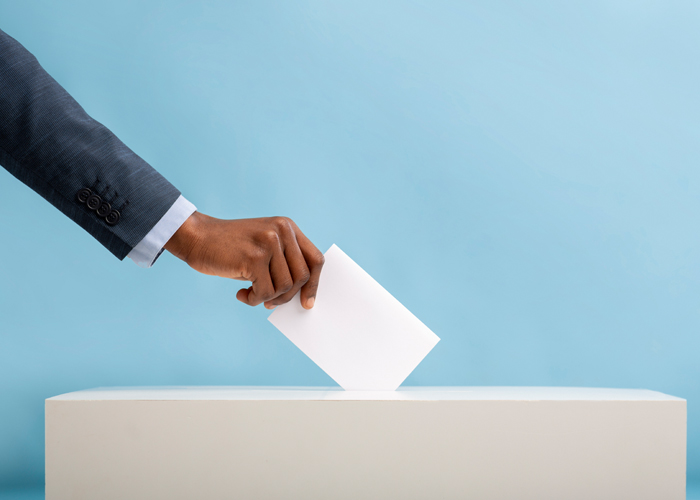 hand placing ballot in voting ballot box