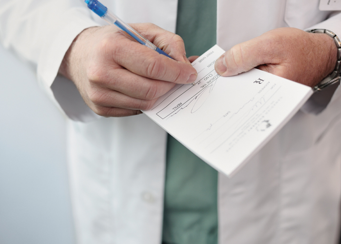 provider hands writing a prescription on a prescription pad