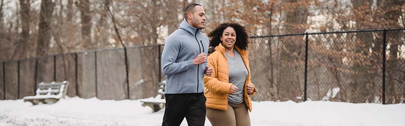 man and woman jogging outdoors in the snow