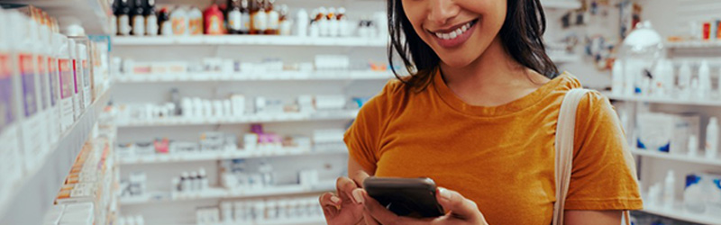 woman in pharmacy looking at mobile phone