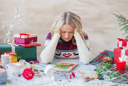 stressed woman wrapping presents holding head