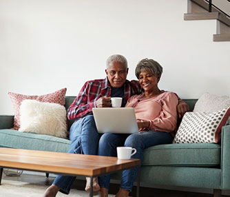 Older couple sitting on the couch looking at open laptop