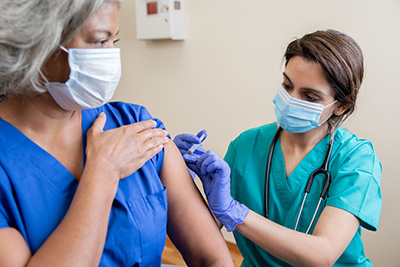 Senior woman receiving a vaccination at a clinic by a nurse