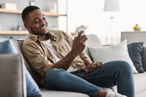 man sitting on sofa looking at mobile phone