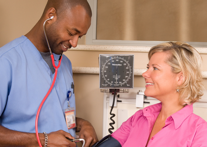 man nurse taking female patient blood pressure stethoscope