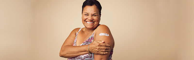 smiling woman with bandage on arm over immunization